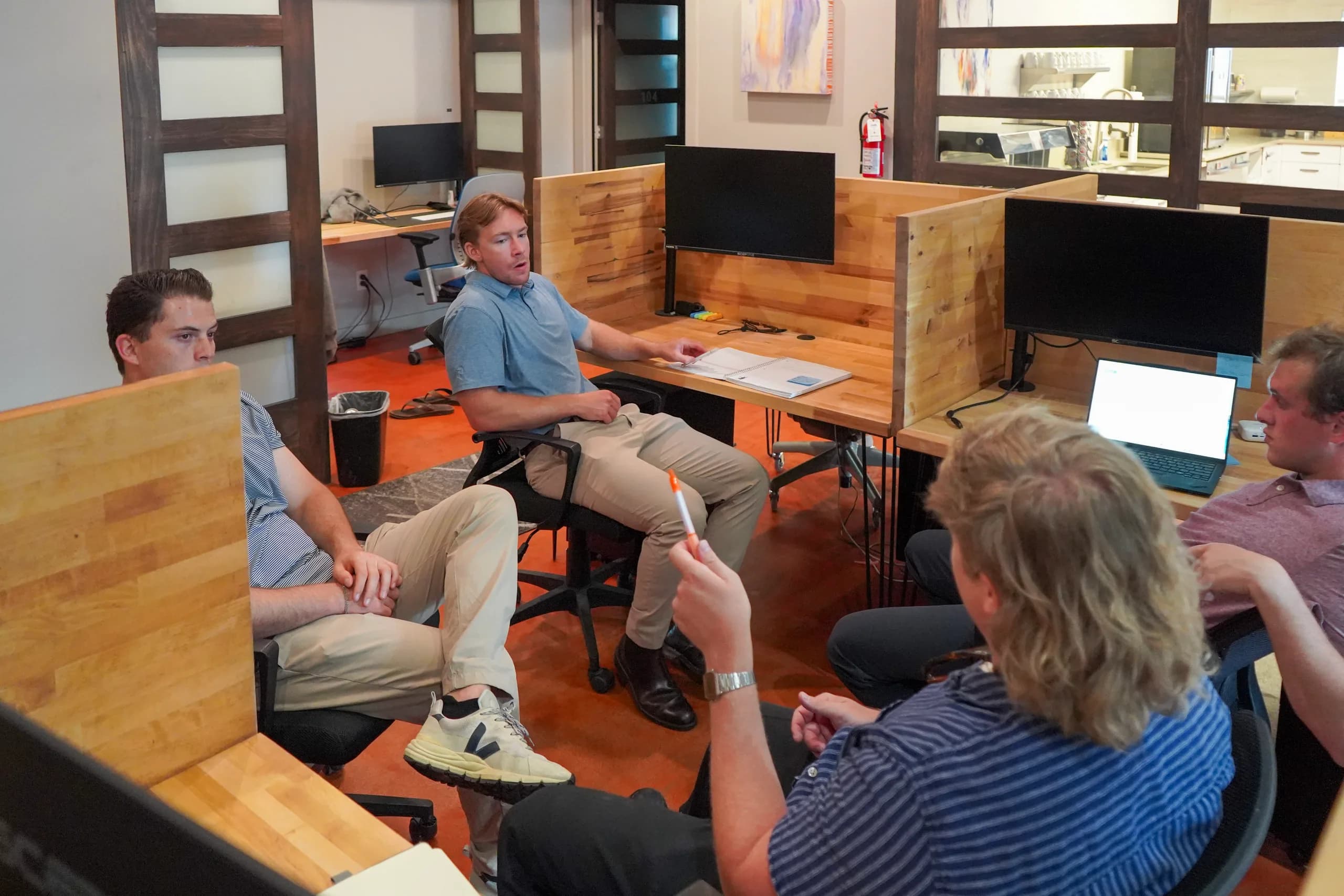 Members talking between the butcher block desk pods in the dedicated desk room at Merritt Workspace, Sloan's Lake, Denver