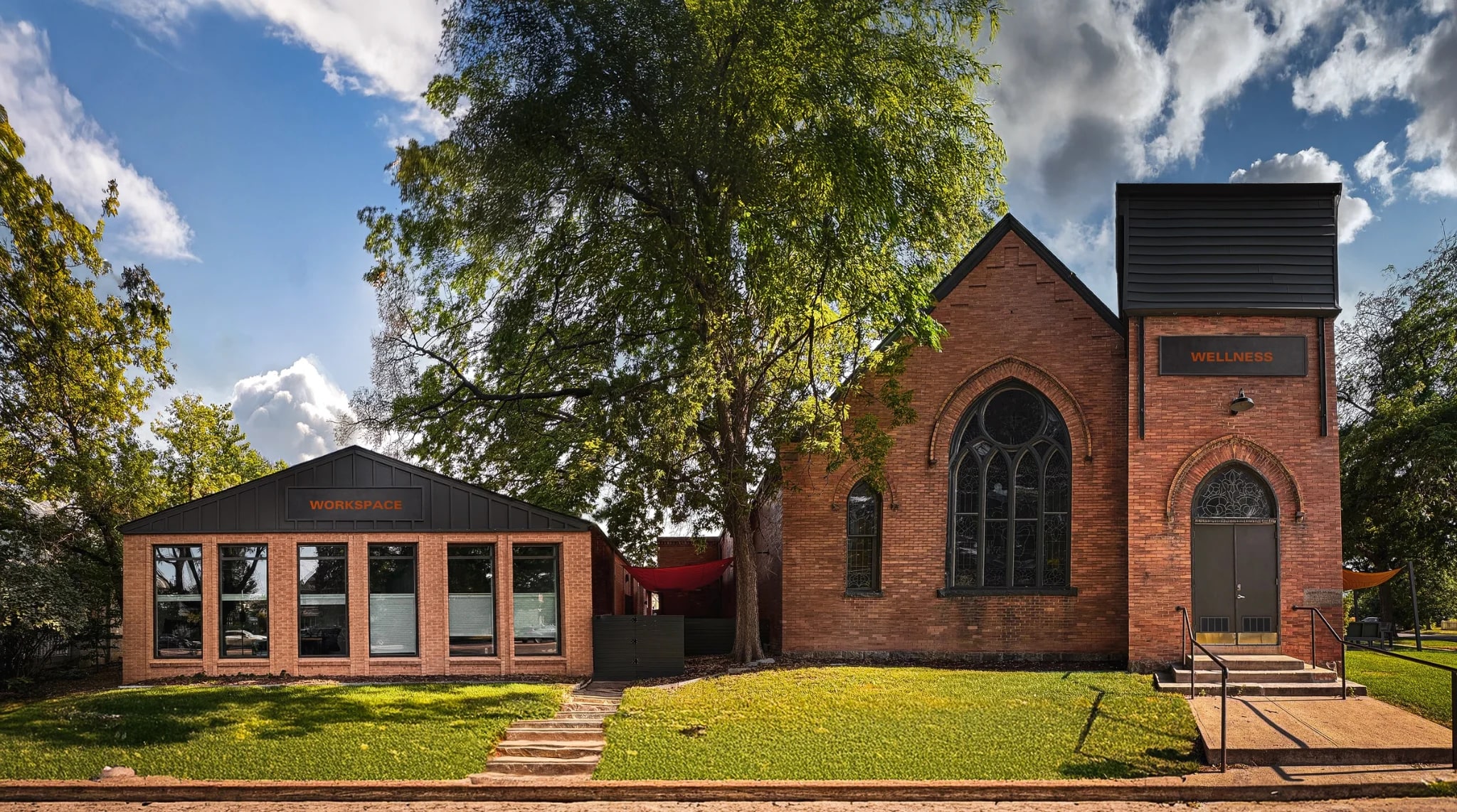 The Merritt Workspace building and the restored 1905 event space side by side on the same lawn at 23rd and Irving, Sloan's Lake, Denver