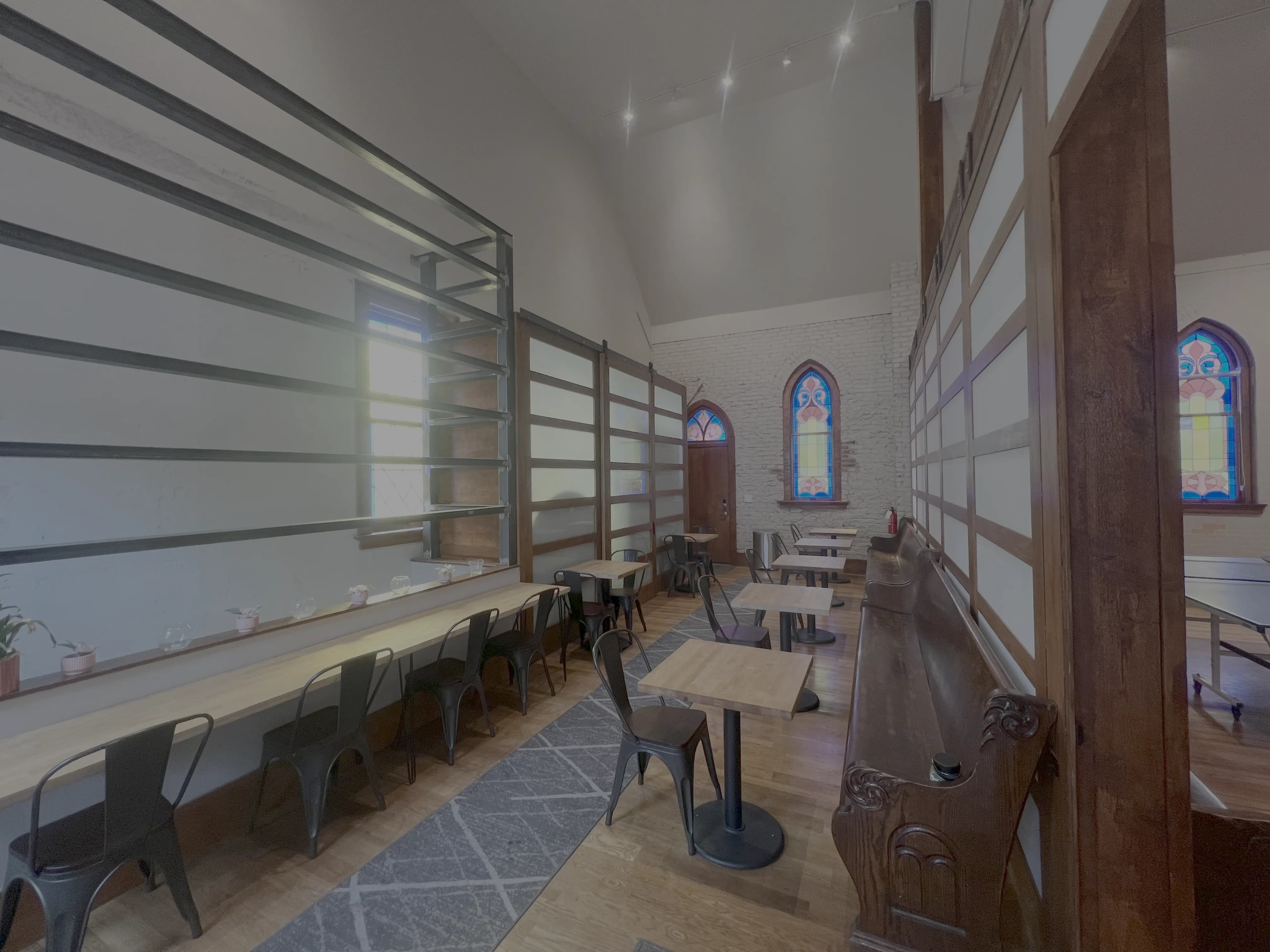 Café seating with table service, hardwood floors and the original stained glass windows at Merritt Workspace, Sloan's Lake, Denver