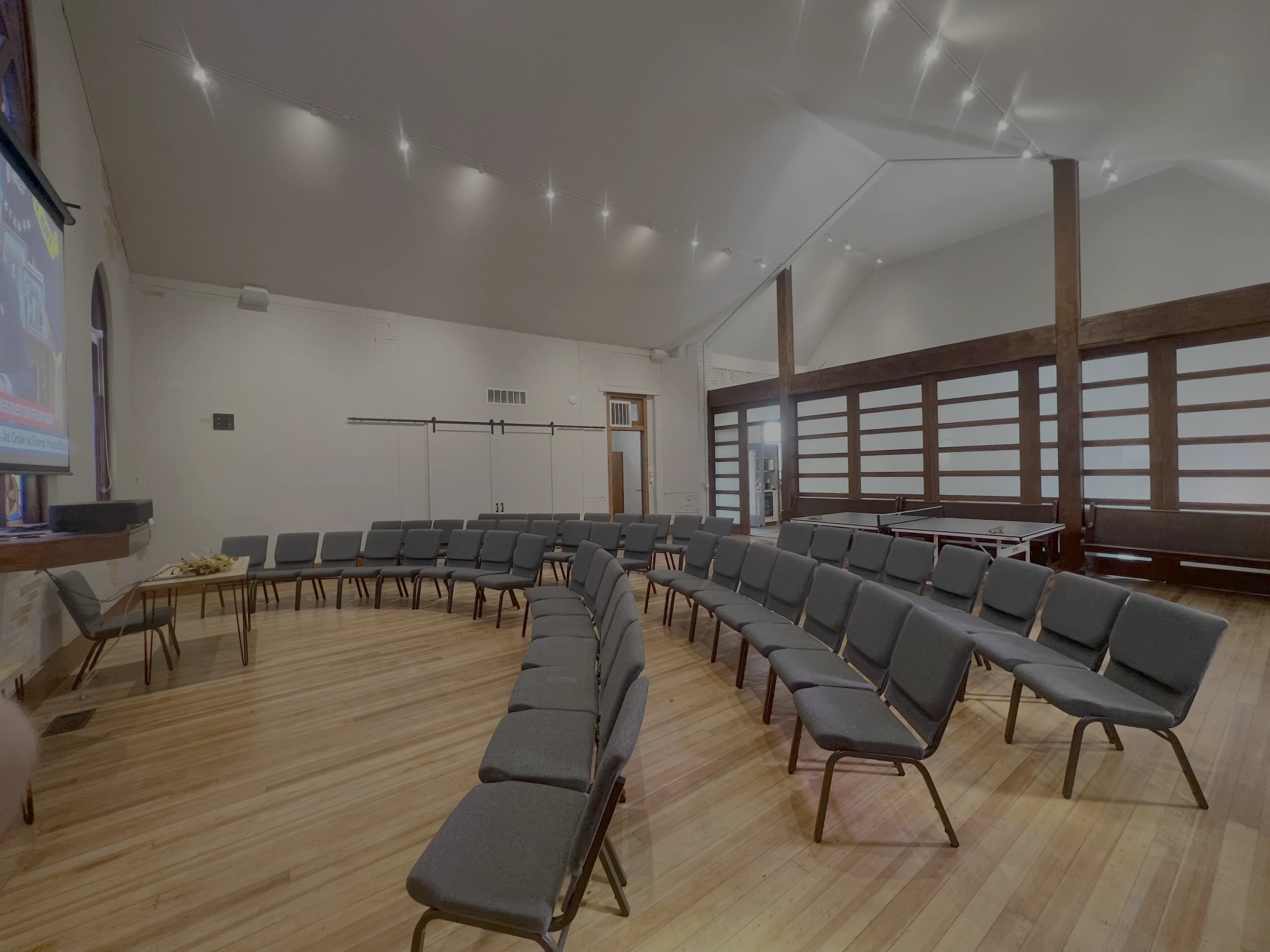 The flex space hall at Merritt Workspace set up with rows of seating facing the projector screen